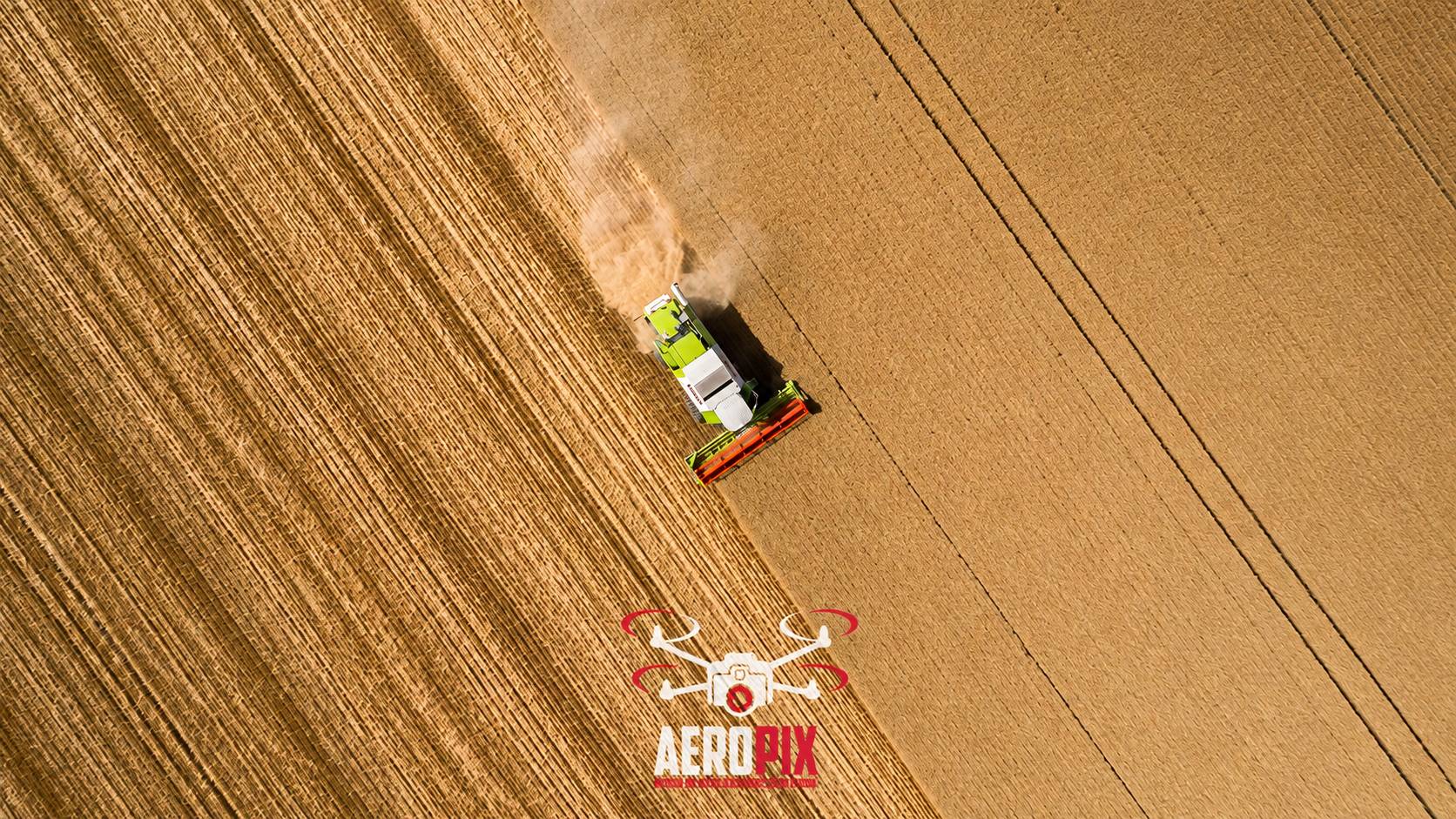 Photo prise par drone d'une moissonneuse-batteuse verte et blanche qui récolte un vaste champ de blé, avec le logo Aeropix en bas.